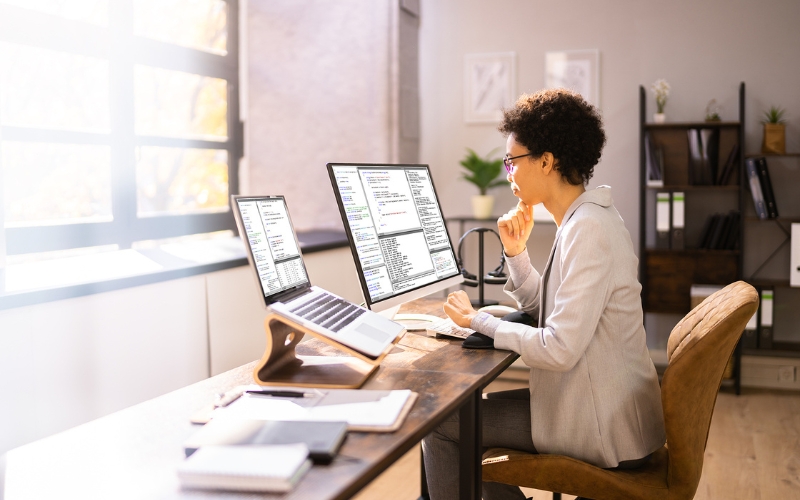 Woman working from home on multiple screens